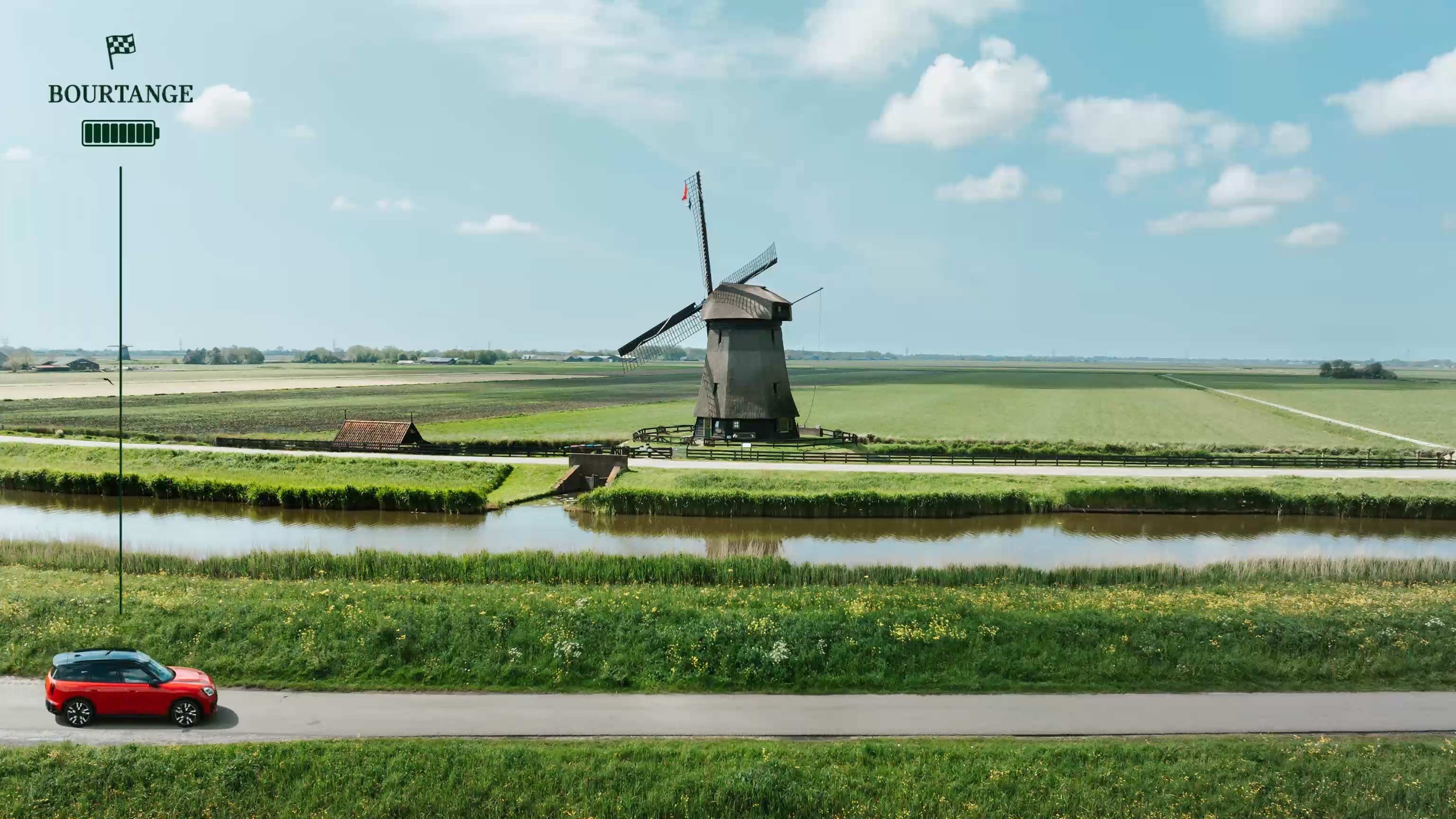 Traditional Dutch mill built on the lush green shores of a small river photographed on a sunny day.